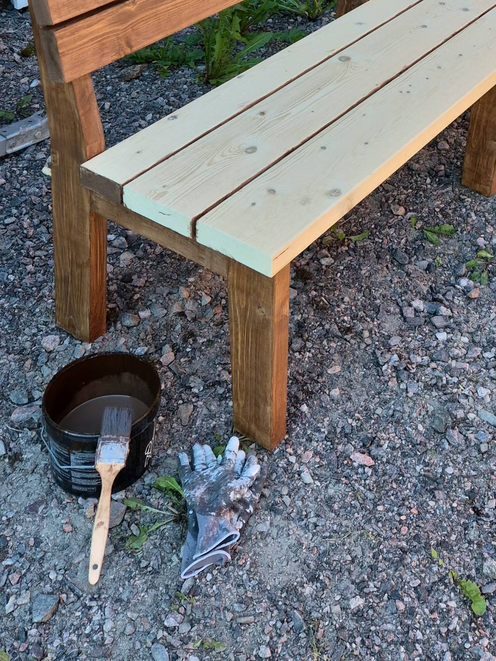 Pensel och färgburk vid en bänk som håller på att behandlas